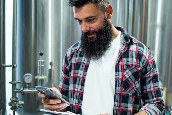 Man with a beard using a smartphone in an industrial setting