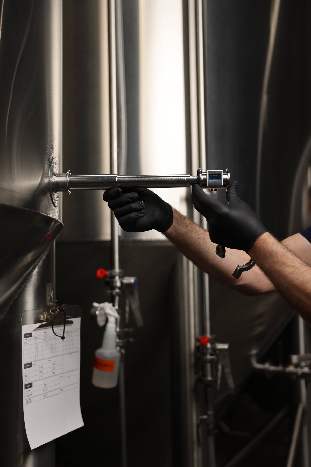 Person wearing gloves adjusting a metal component on a tank.