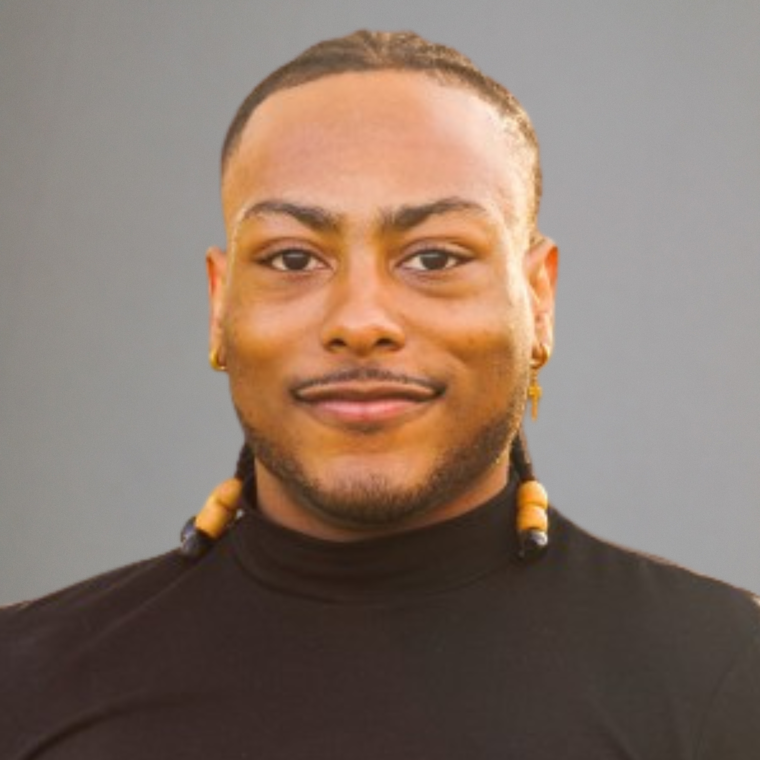 Man wearing a black turtleneck with yellow beads against a gray background