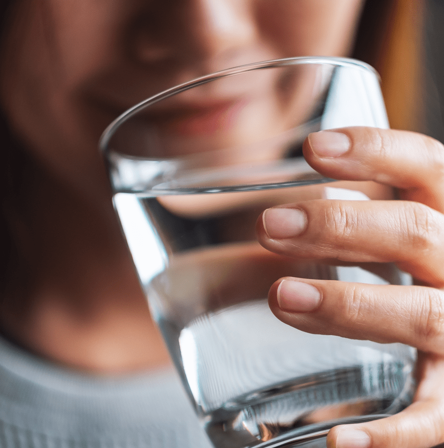 Person holding a glass of water with a blurred background